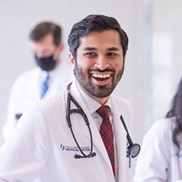 resident in white coat smiling with stethoscope draped over shoulders